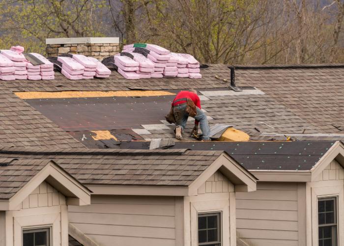 A contractor installing new asphalt shingle roofing.